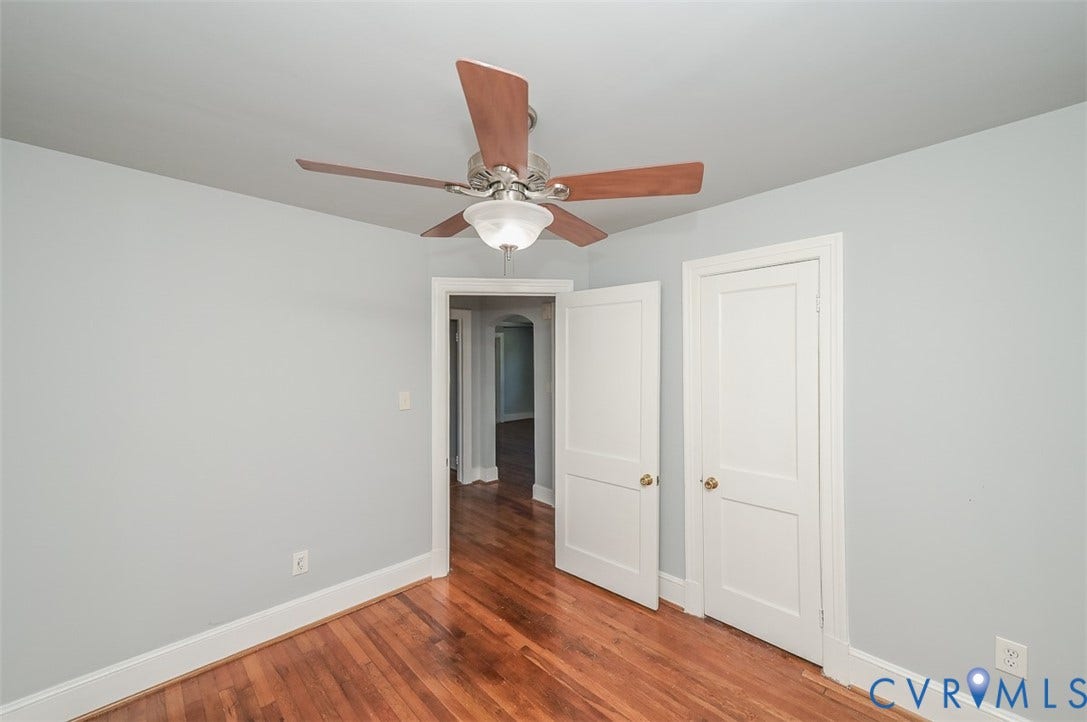 Hardwood flooring, ceiling fan with integrated lighting, white trim, and interior doors with gold-tone hardware