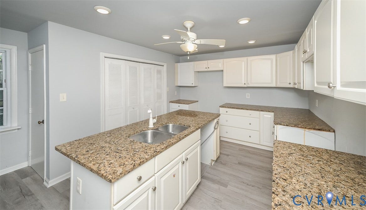 Kitchen featuring white cabinetry, granite countertops, a center island with a double basin sink, wood-finish flooring, and recessed lighting