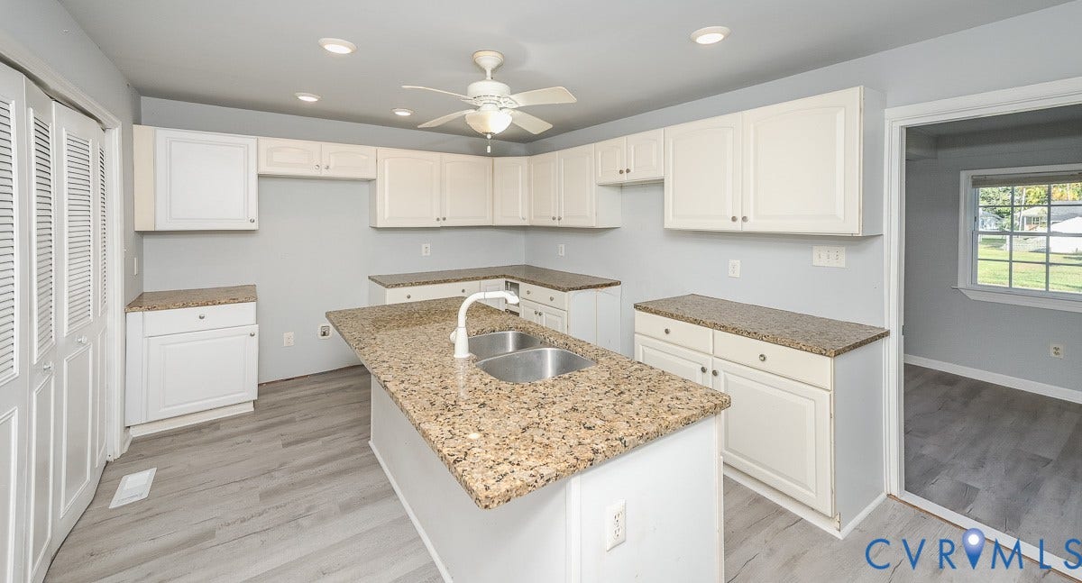 U-shaped kitchen layout with an island, white cabinetry, granite-finish countertops, and wood-finish flooring