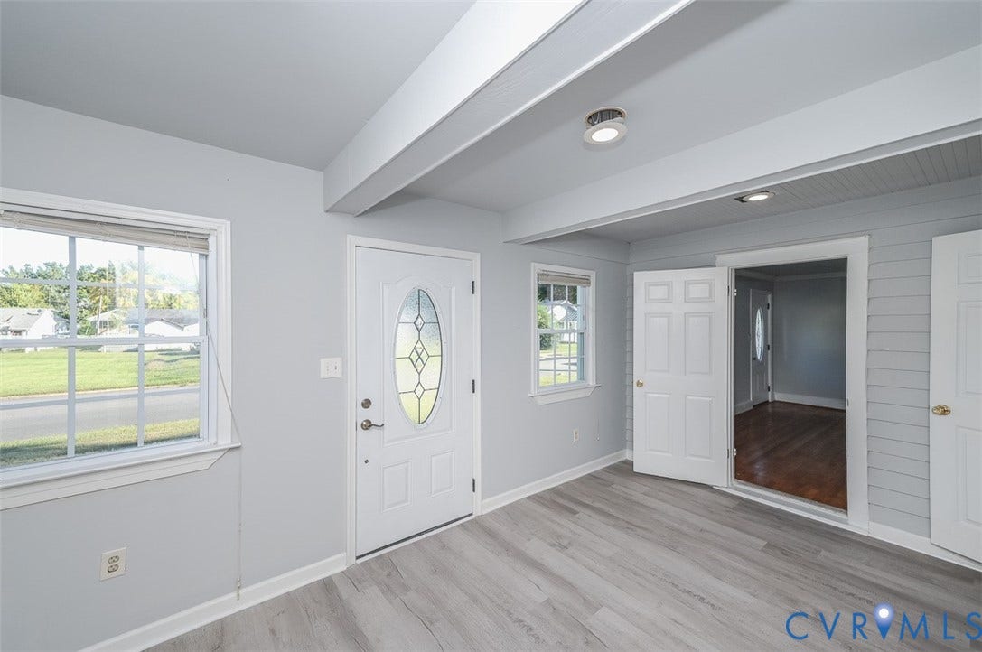Wood-finish flooring, white paneled doors, beam ceiling, recessed lighting, and a front entry door with decorative glass