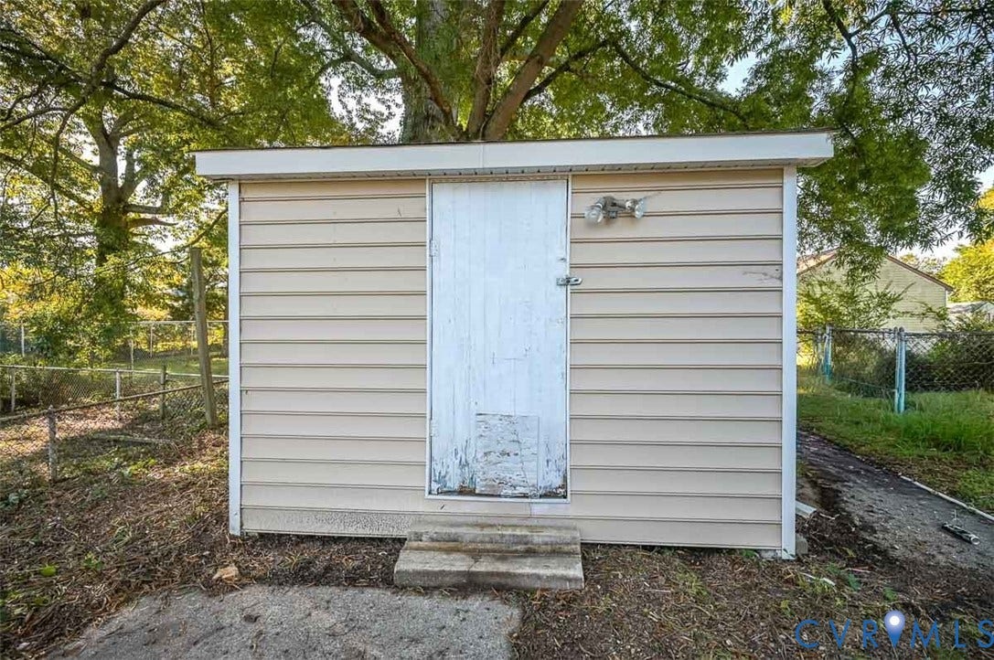 Outbuilding with tan horizontal siding, white trim, and a white flat roof