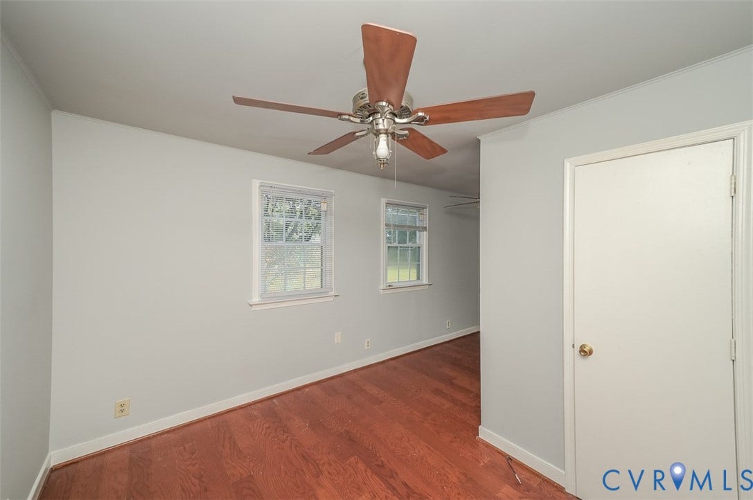 Hardwood flooring, two windows, ceiling fan with light fixture, and white interior door
