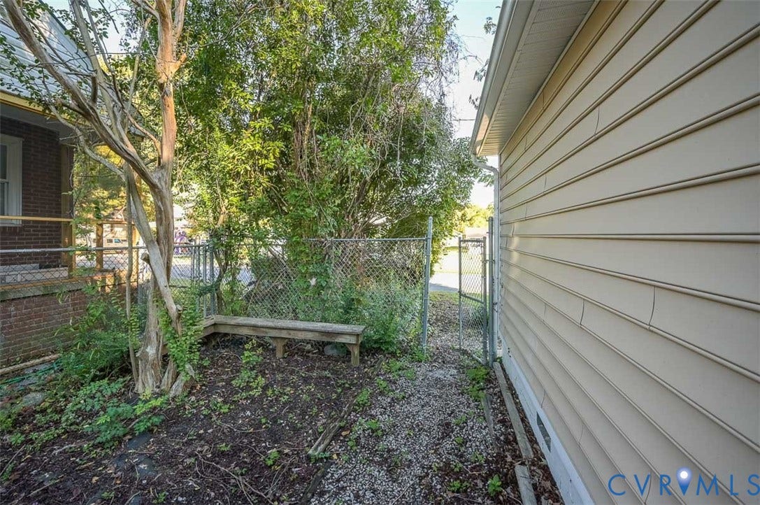 Chain link fencing with mature trees and a wood bench