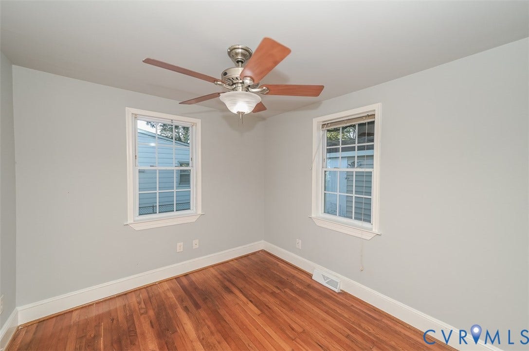 Hardwood flooring, painted walls, ceiling fan with integrated lighting, and two windows with white trim