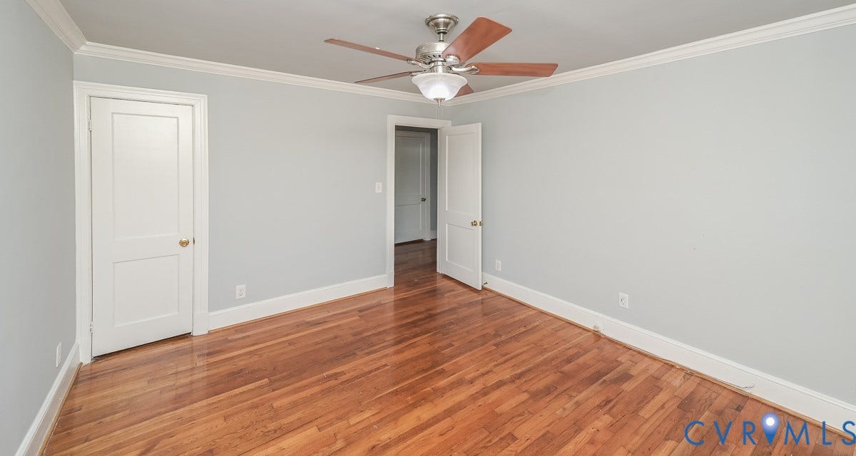 Wood-finish flooring, crown molding, and a ceiling fan with light fixture