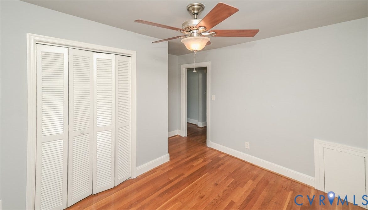 Hardwood flooring, ceiling fan with integrated lighting, louvered bi-fold closet doors, and light gray wall paint