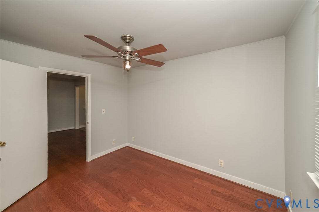 Wood-finish flooring, ceiling fan with integrated lighting, neutral wall paint, and window with blinds