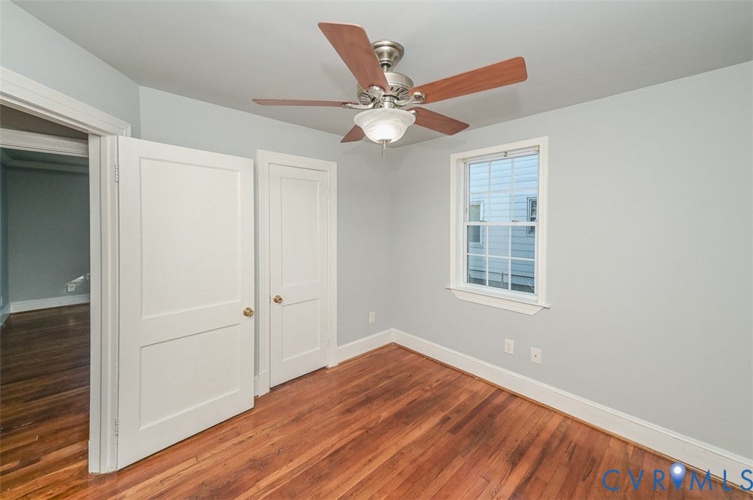 Wood-finish flooring, ceiling fan with light fixture, single window, and two panel doors