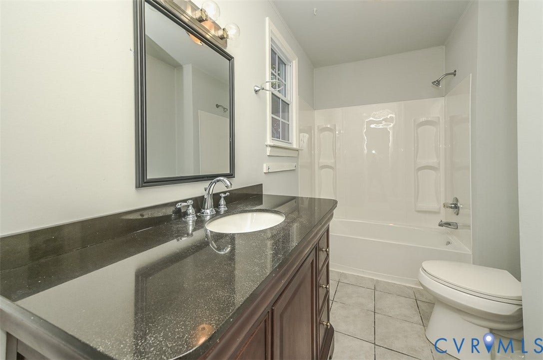 Dark stone countertop vanity with an integrated sink and chrome fixtures