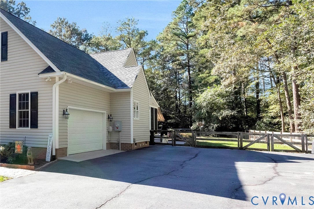 360 Laurel Drive, Aylett, VA 23009 Siding exterior with a dark shingle roof, attached garage, paved driveway, and a wood fence