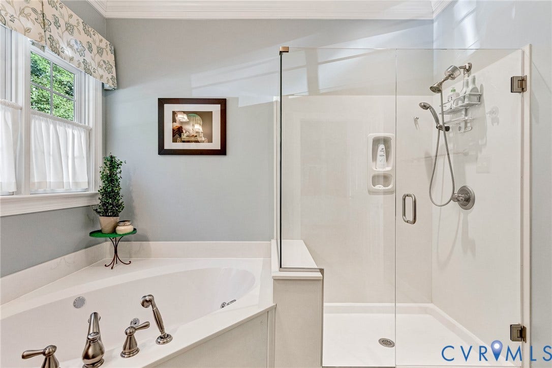 360 Laurel Drive, Aylett, VA 23009 Corner soaking tub with brushed nickel fixtures, glass-enclosed shower, and window with white trim