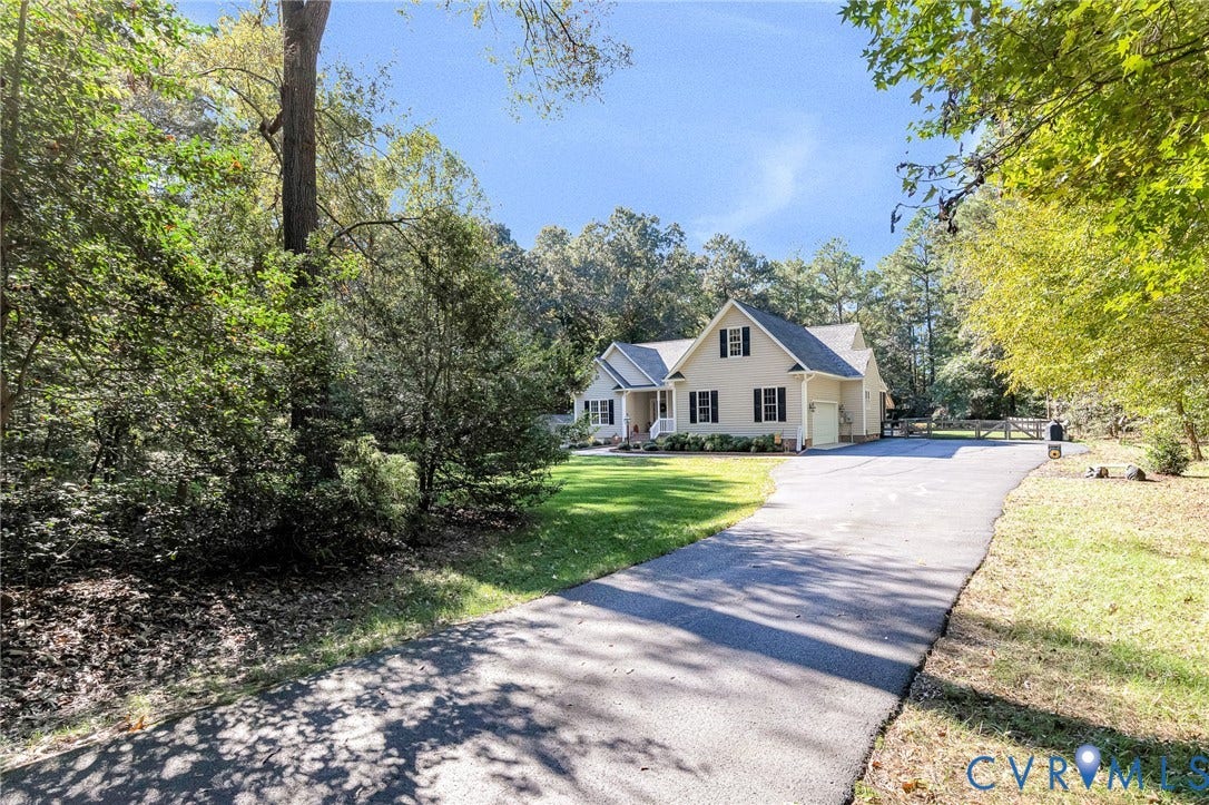 360 Laurel Drive, Aylett, VA 23009 Cream-colored siding residence with black shutters, an attached garage, and a long paved driveway, surrounded by mature trees and manicured lawn