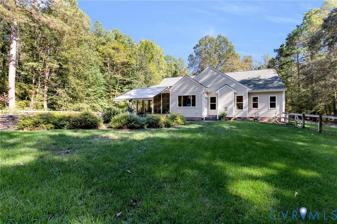 360 Laurel Drive, Aylett, VA 23009 Expansive green lawn with a white-paneled exterior, screened-in porch, and a stone retaining wall, all surrounded by mature trees