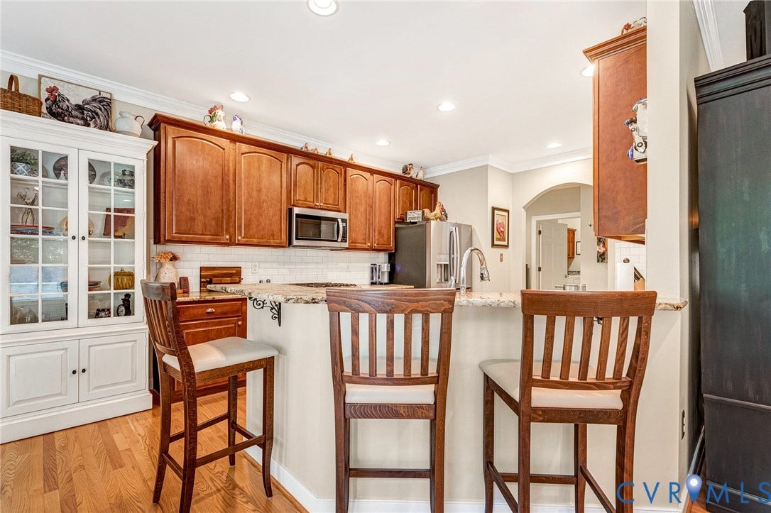 360 Laurel Drive, Aylett, VA 23009 Chef's kitchen featuring custom wood cabinetry, stainless steel appliances, white subway tile backsplash, and a center island with seating