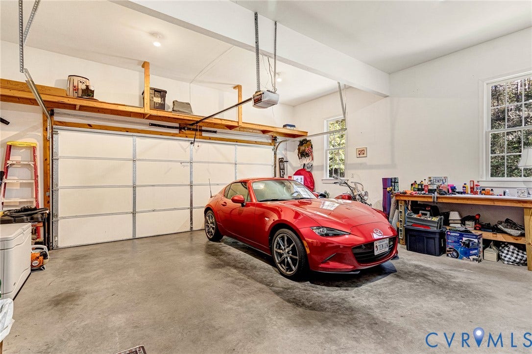 360 Laurel Drive, Aylett, VA 23009 Spacious garage featuring concrete flooring, a dual garage door, built-in overhead storage shelving, and multiple windows