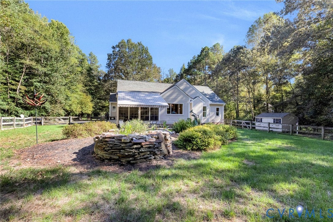 360 Laurel Drive, Aylett, VA 23009 Expansive backyard featuring a manicured lawn, established garden beds with stone edging, and a detached storage shed