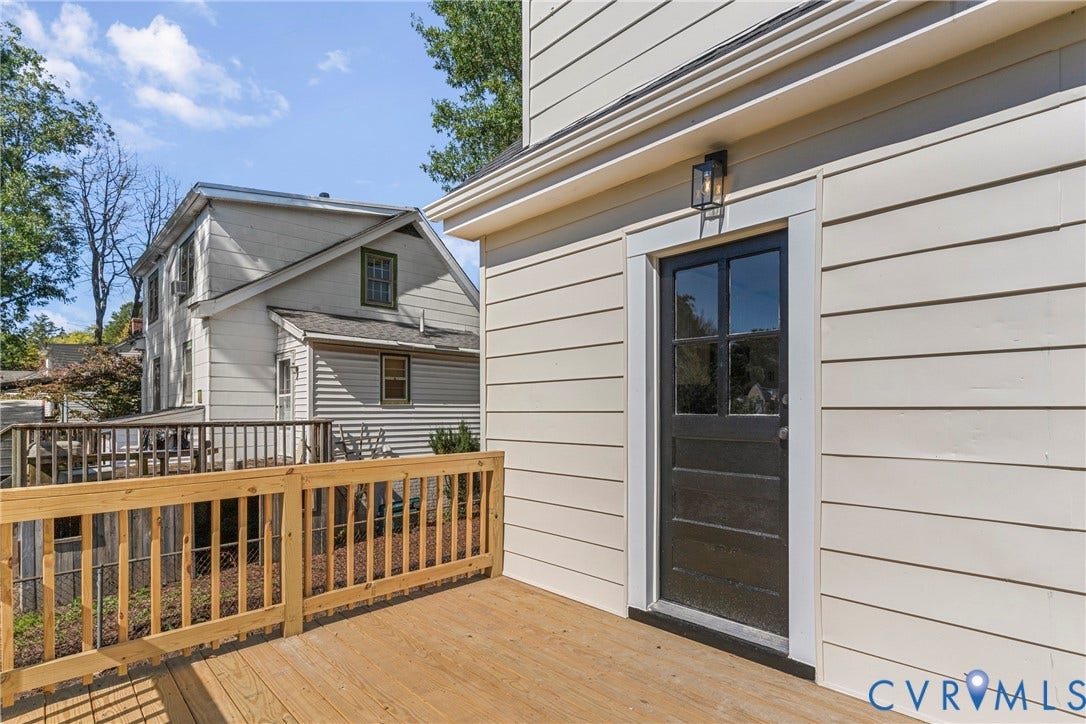2601 Greenway Avenue, Lakeside, Henrico, VA 23228 Exterior deck with horizontal wood railing, light-toned horizontal siding, and black-painted paneled door with glass upper panes, accented by a wall-mounted lantern light fixture