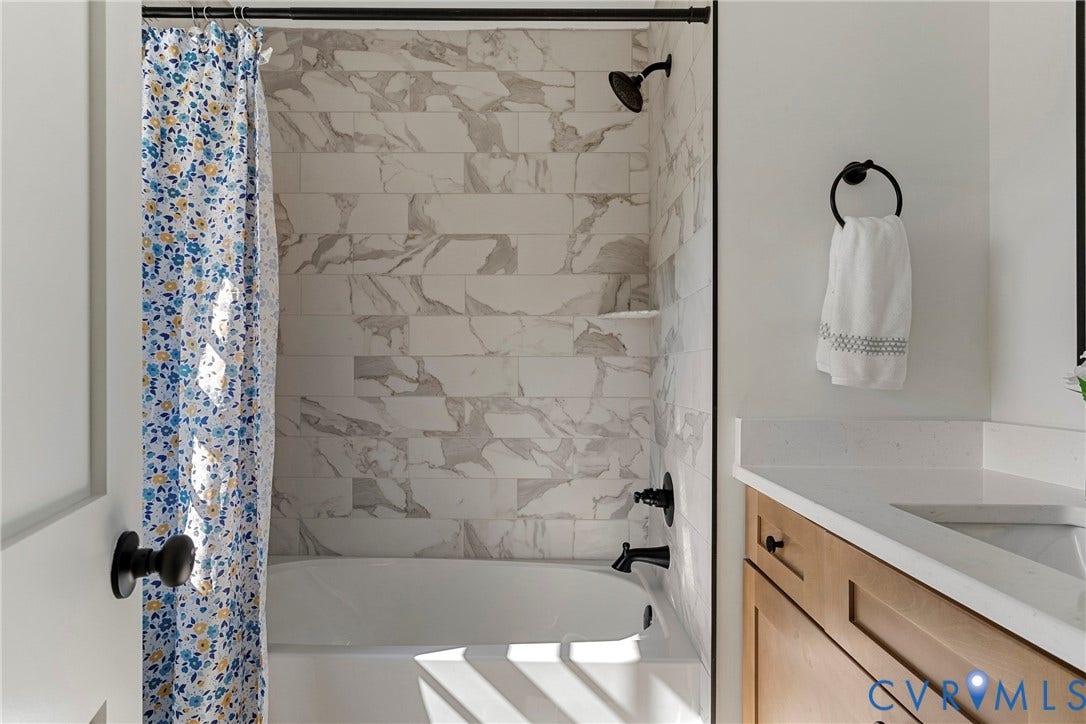 2601 Greenway Avenue, Lakeside, Henrico, VA 23228 Bathroom featuring a built-in tub with stone-patterned tile surround, matte black shower fixtures, light wood-finish vanity cabinetry, and a white countertop with an integrated sink