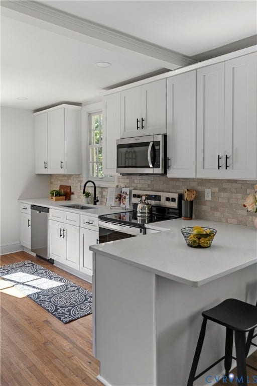 2601 Greenway Avenue, Lakeside, Henrico, VA 23228 Kitchen featuring white shaker-style cabinetry, solid-surface countertops, stone-tile backsplash, stainless steel appliances, and wood-finish flooring