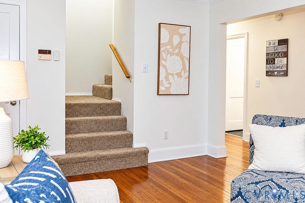 Hardwood flooring, painted white baseboards, and a carpeted staircase with a wood handrail
