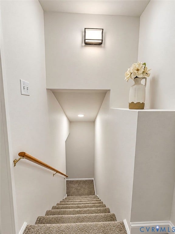 Carpeted staircase with a wood-finish handrail and integrated wall lighting