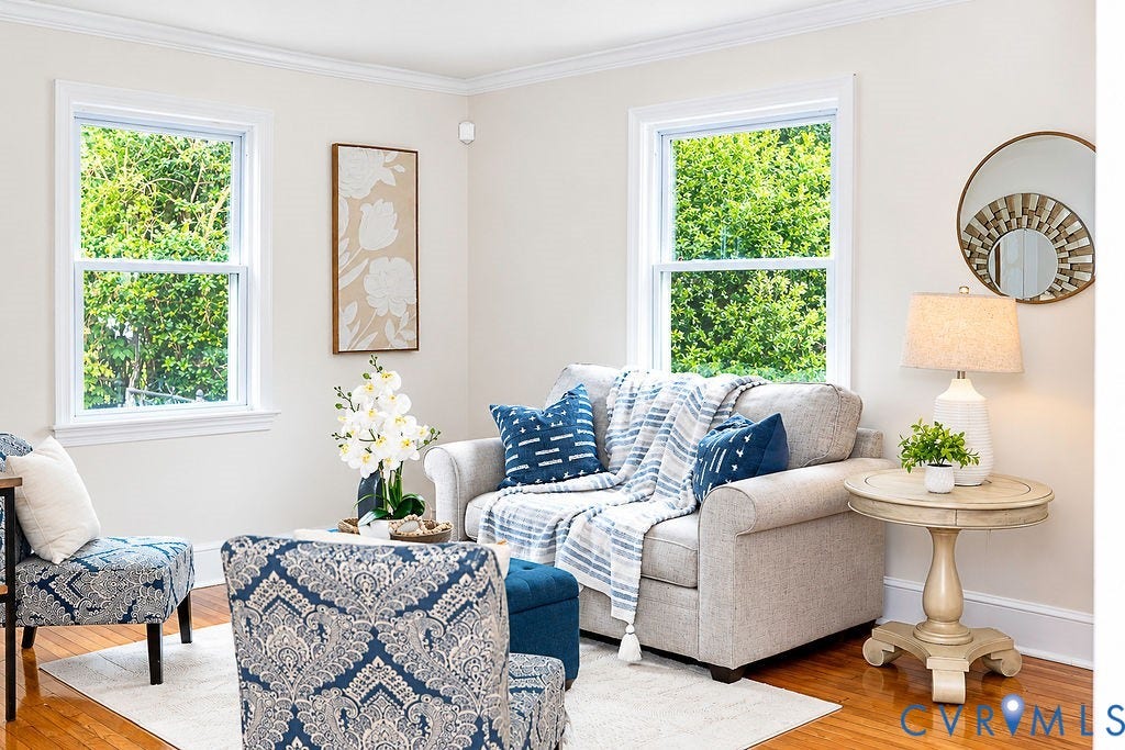Light-colored walls, wood-finish flooring, two windows with white trim, and crown molding
