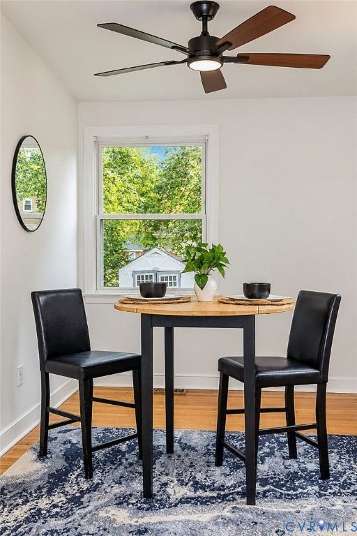 Ceiling fan with integrated lighting, wood-finish flooring, and bright white walls
