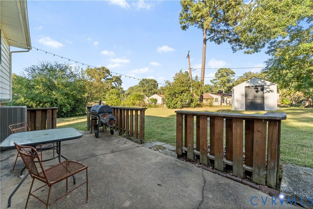 109 Webster Road, Sandston, VA 23150 Concrete patio area with wood railings, expansive lawn, and storage shed