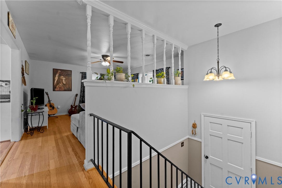 109 Webster Road, Sandston, VA 23150 Hardwood-finish flooring, white spindle railing, black wrought iron railing, white paneled door, and a multi-light chandelier
