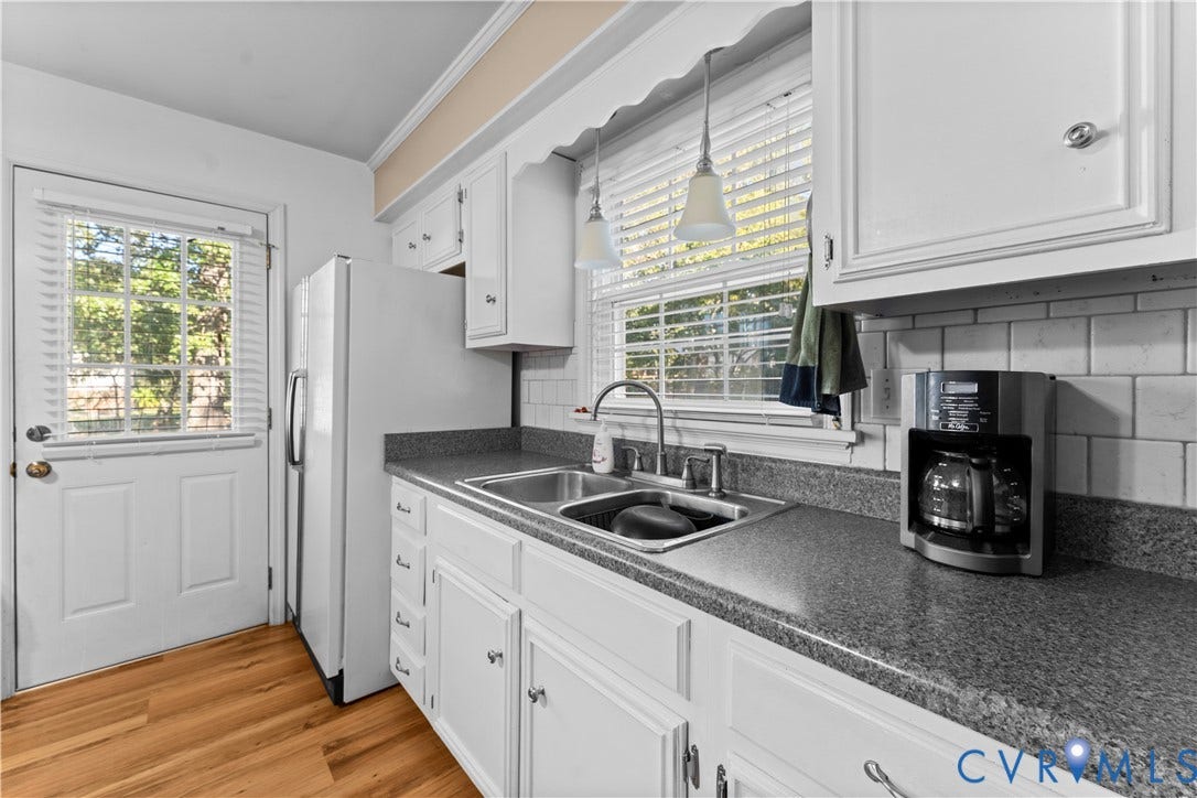 109 Webster Road, Sandston, VA 23150 Wood-finish flooring, white cabinetry, dark speckled countertops, subway tile backsplash, and a stainless steel double-basin sink