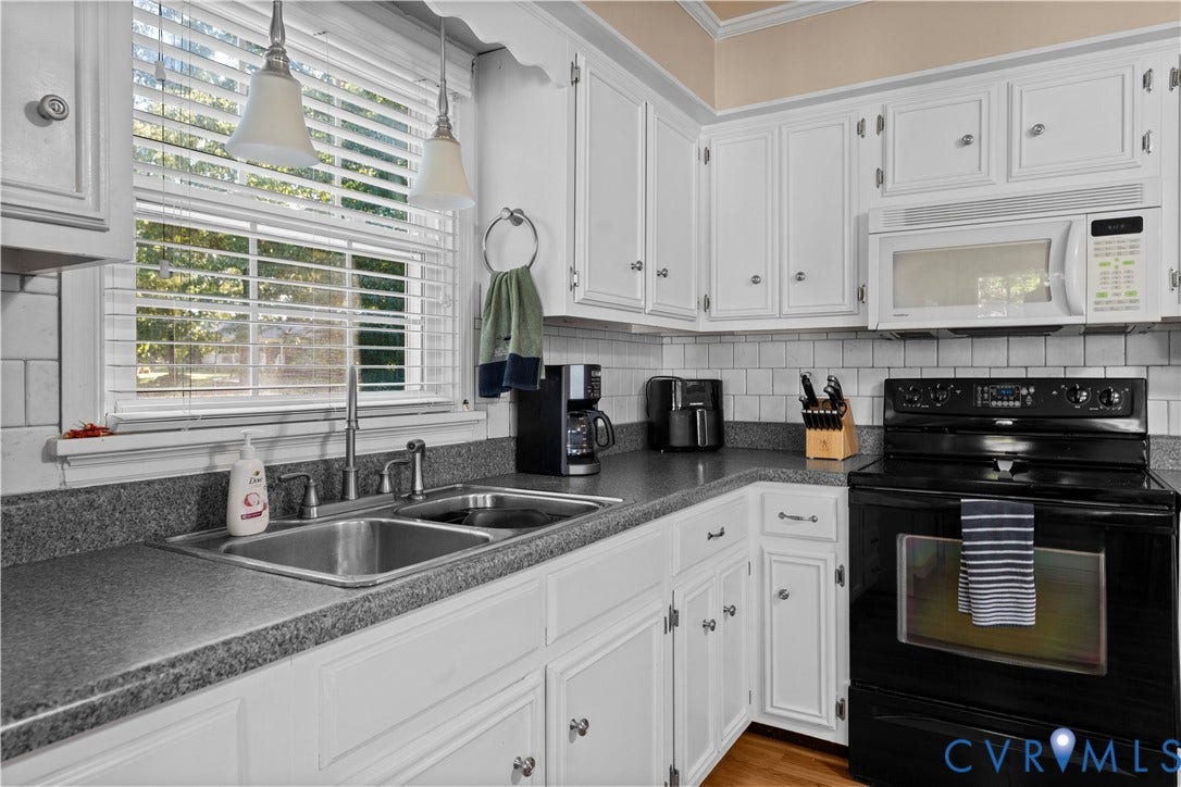 109 Webster Road, Sandston, VA 23150 White cabinetry, dual basin stainless steel sink, black electric range, white microwave, and subway tile backsplash