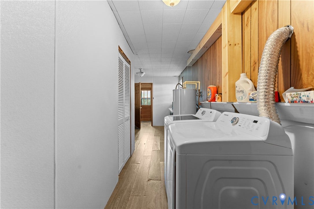109 Webster Road, Sandston, VA 23150 Efficient laundry room featuring side-by-side washer and dryer appliances, wood-finish flooring, white cabinetry with integrated storage, stainless steel sink with chrome faucet, and abundant overhead lighting throughout the corridor-style layout