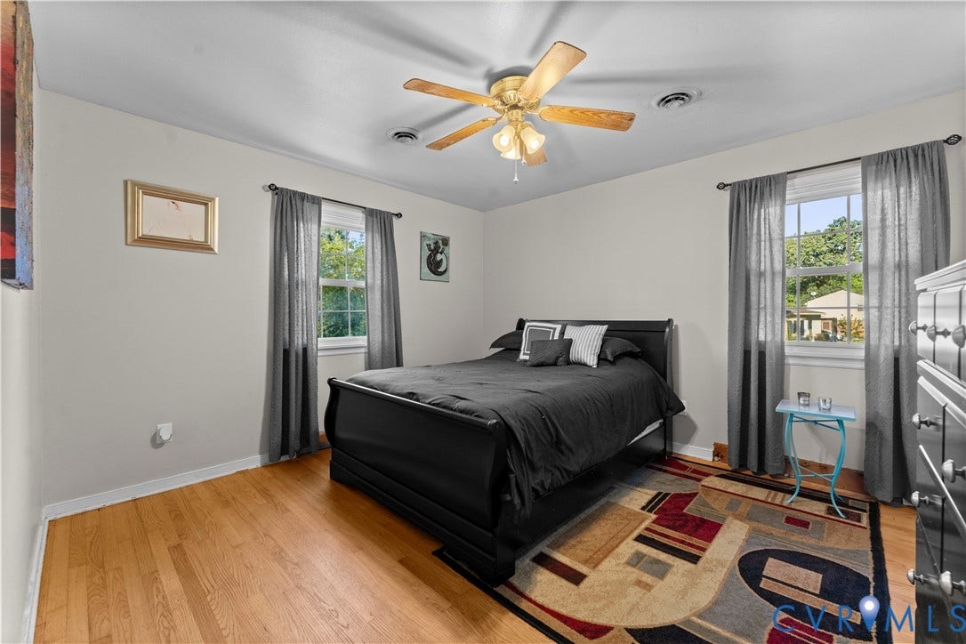 109 Webster Road, Sandston, VA 23150 Hardwood flooring, two windows with window treatments, ceiling fan with light fixture, and light-toned wall paint