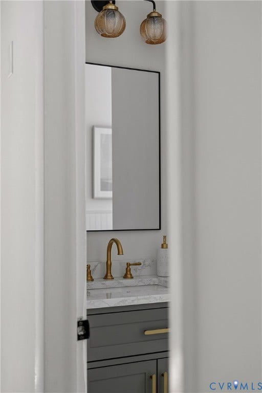 5304 Gillespie Avenue, Henrico, VA 23228 Wall-mounted vanity light fixtures, framed mirror, gold-finish faucet, stone-finish countertop, and gray vanity cabinetry