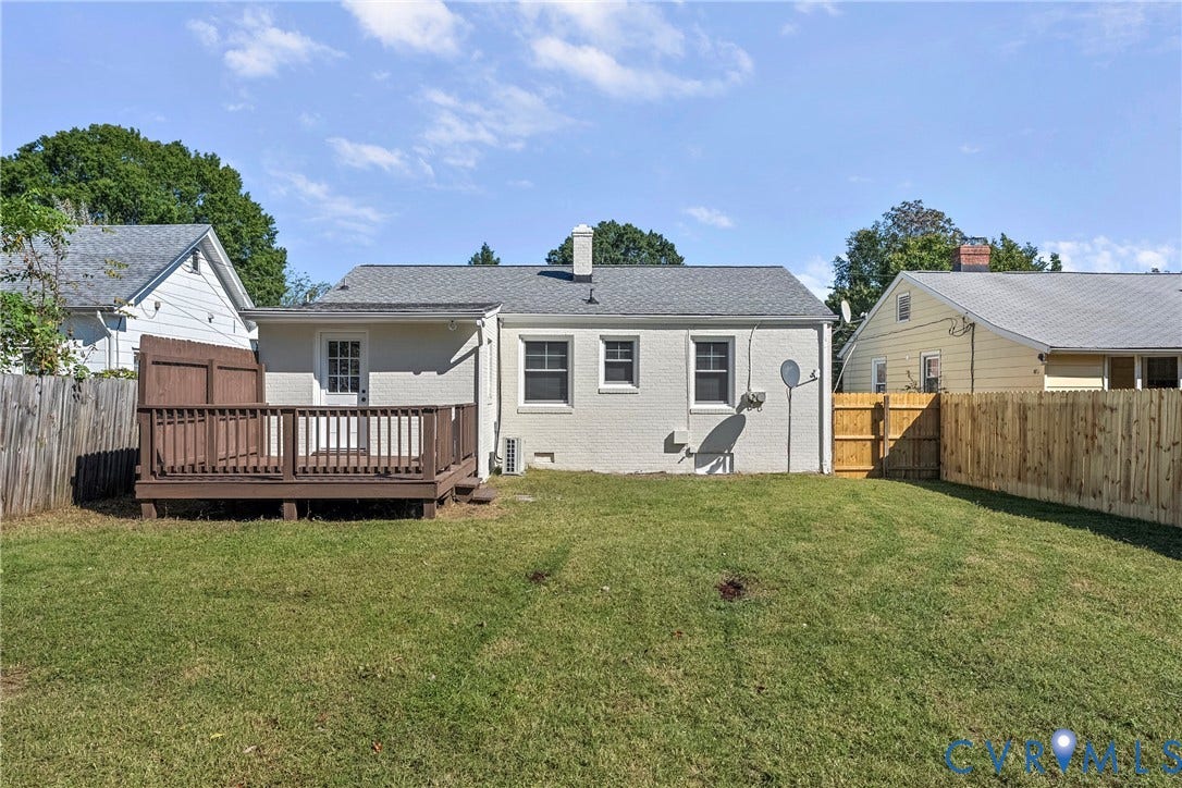 5304 Gillespie Avenue, Henrico, VA 23228 Expansive grassy backyard featuring a wooden deck, a wooden privacy fence, and a gate