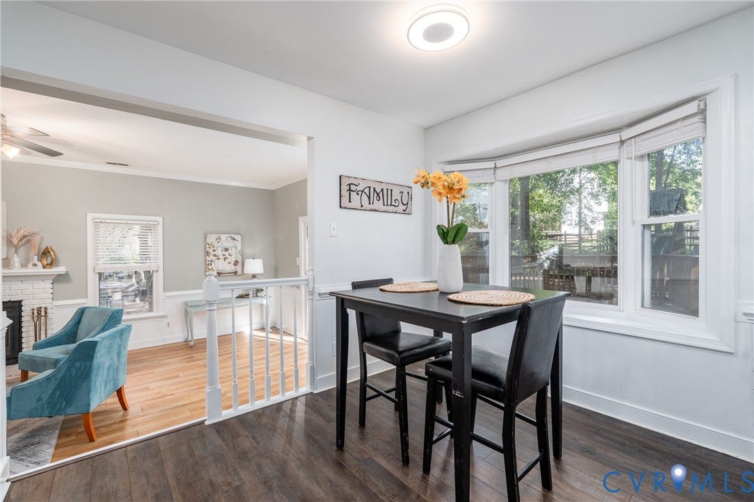 Wood-finish flooring throughout, bay window with blinds, recessed lighting, and a white painted banister.