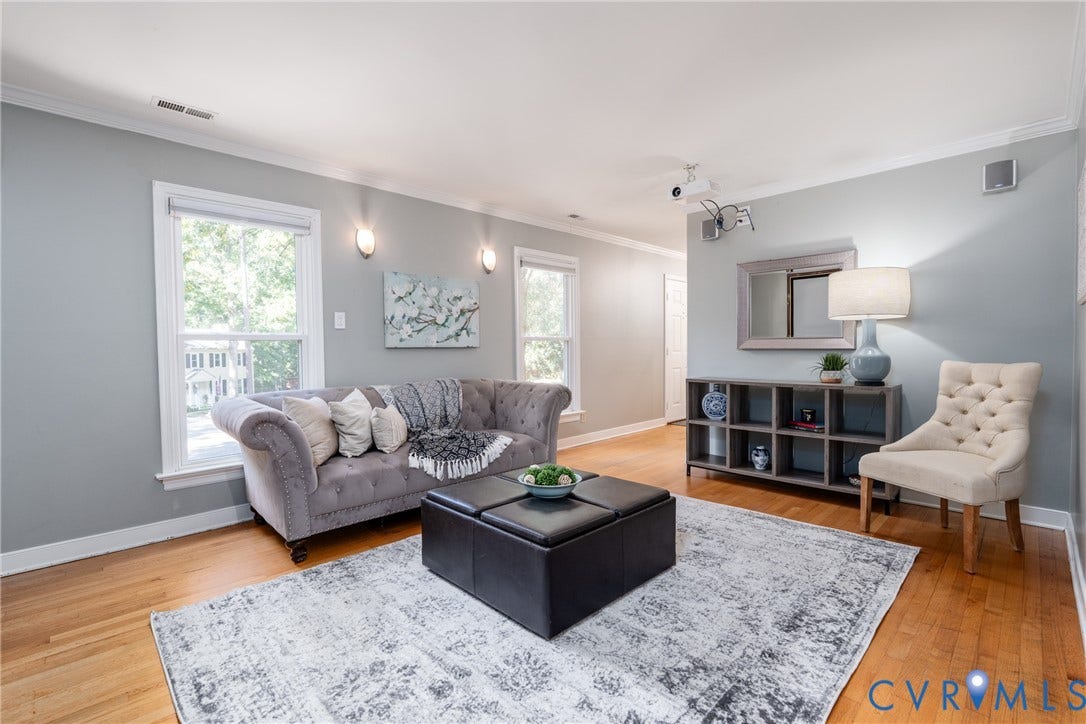 Hardwood flooring, crown molding, double windows, wall-mounted sconces, and a built-in shelving unit