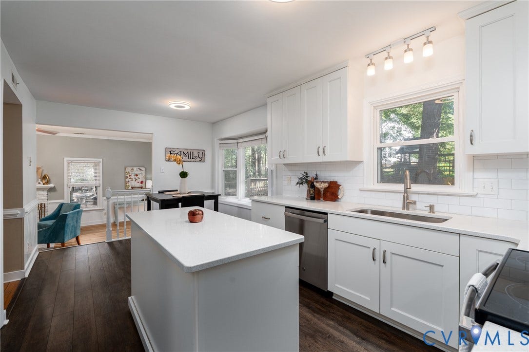 White shaker cabinetry, light-toned countertops, stainless steel appliances, dark wood-finish flooring, and a subway tile backsplash.