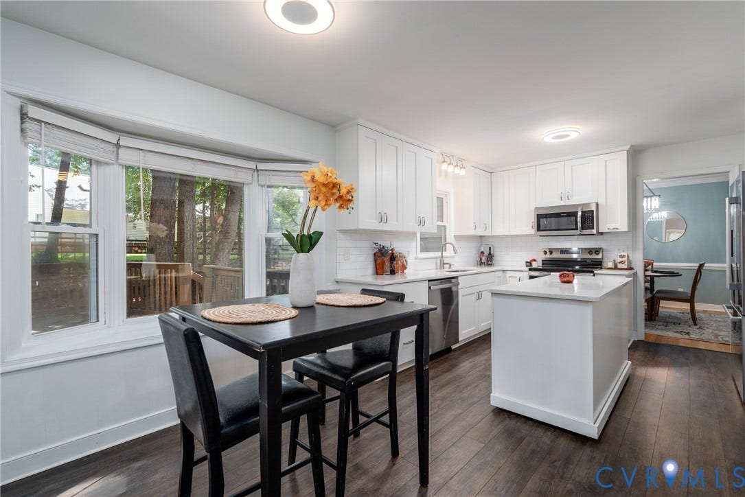 Kitchen featuring white shaker-style cabinetry, stainless steel appliances, a center island with countertop, and wood-finish flooring