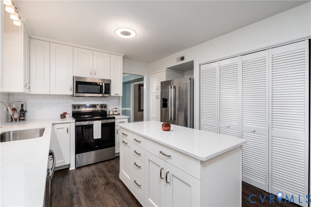 Kitchen featuring white shaker cabinetry, stainless steel appliances, wood-finish flooring, white subway tile backsplash, and a central island with a solid surface countertop