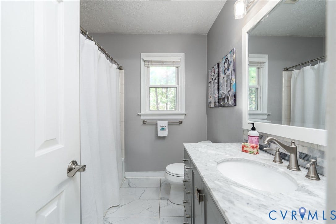 Bathroom featuring a single window, a built-in vanity with an undermount sink, a framed mirror, and tile flooring.