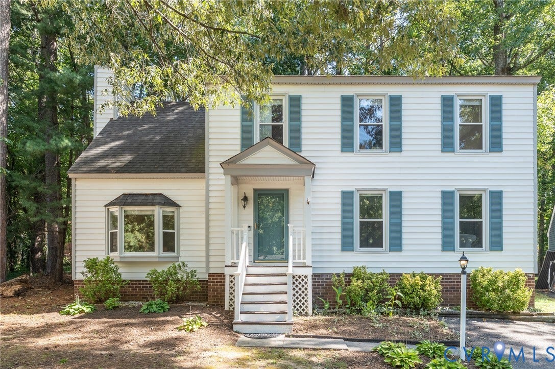White siding exterior with blue shutters, a covered entry porch, a bay window, and an exterior light post.