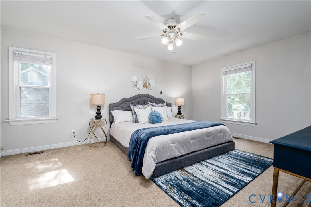 Carpeted flooring with multiple windows, a ceiling fan, and light-toned walls