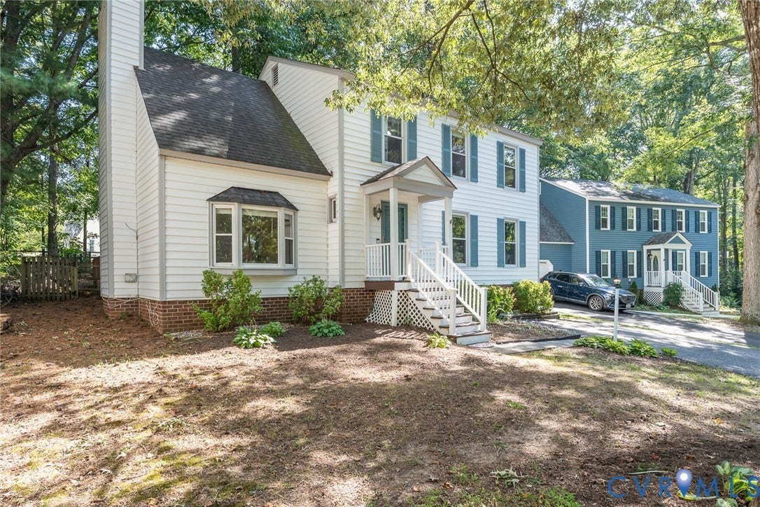 Two-story exterior with white siding, bay window, and blue window shutters