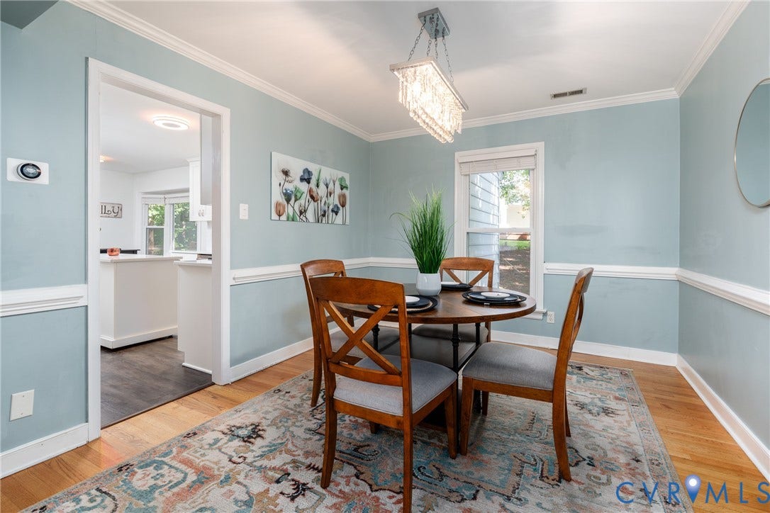 Hardwood flooring throughout, crown molding, chair rail molding, and a crystal chandelier.