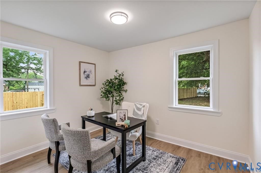 Recessed ceiling lighting, two windows with white trim, light-colored wall paint, and wood-finish flooring