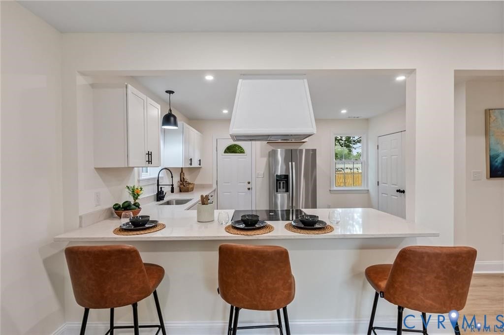 Kitchen featuring white cabinetry, light-toned countertops, a stainless steel refrigerator, and recessed lighting