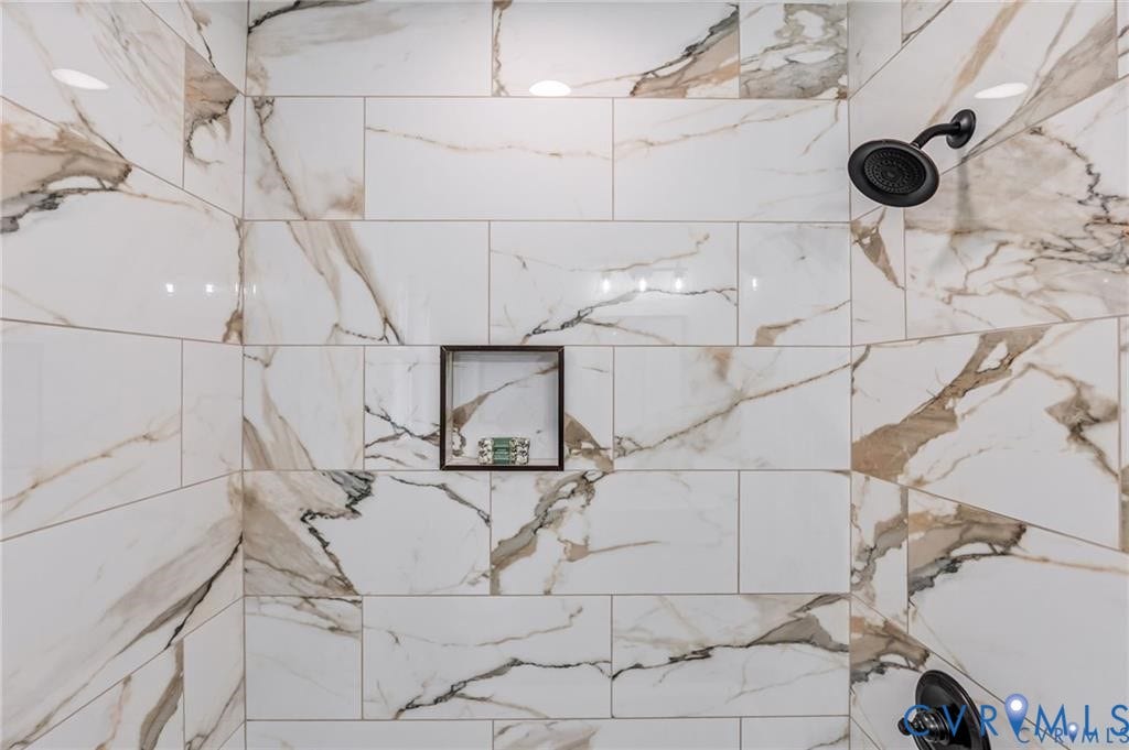 Marble-look tile shower with a built-in niche and dark-finish fixtures