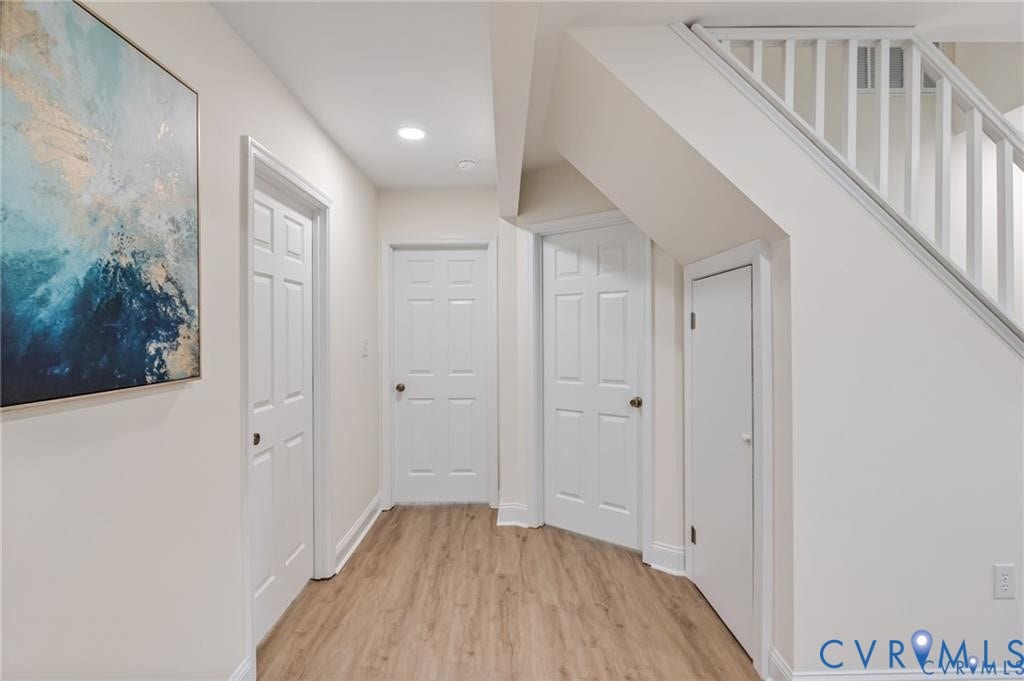 Wood-finish flooring, recessed lighting, white paneled doors, and white painted walls