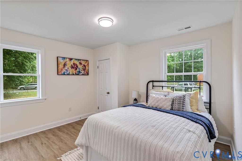 Wood-finish flooring with white trim, two white-framed windows, and a flush-mount ceiling light